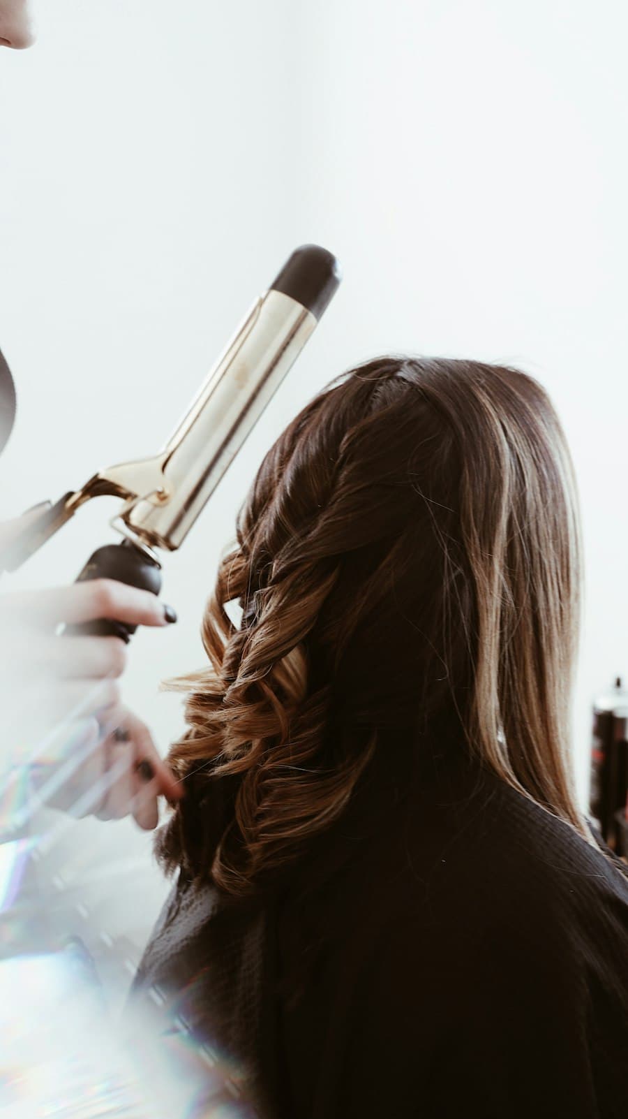 Curling iron setting a loose wave in long brunette hair